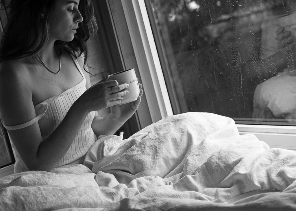 Woman in bed holding a cup of coffee